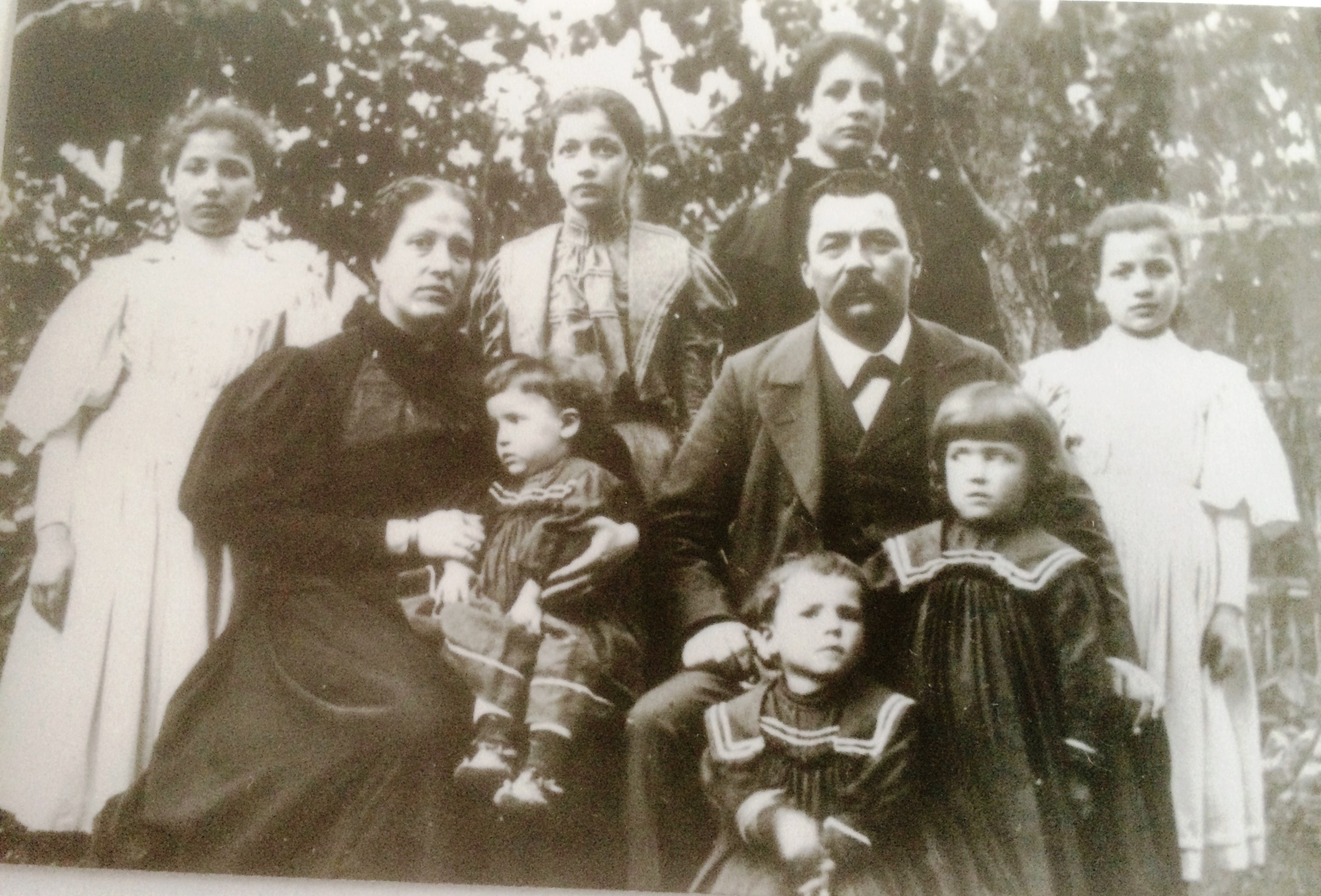 Fotografija 3: Družina Pertot iz Rojana. Rojanski nadučitelj in
                        sokolski načelnik Josip (Jože) Pertot in Ana, roj. Štrukelj, iz Trebč
                        (Trebicino) s sedmimi od osmih hčera: najstarejša Ilka (Otilija), por. Stegu, ki je po prvi svetovni vojni edina
                        ostala v Italiji, Marija (Mimi), por. Fornazarič, Stanislava (Stana), por.
                        Gulič, Nada, por. Mrkušić, Ana, por. Schäffer, Milka (Emilija), ki ni bila
                        poročena, Zorka, por. Kisić, in najmlajša Vera, por. Grgič.