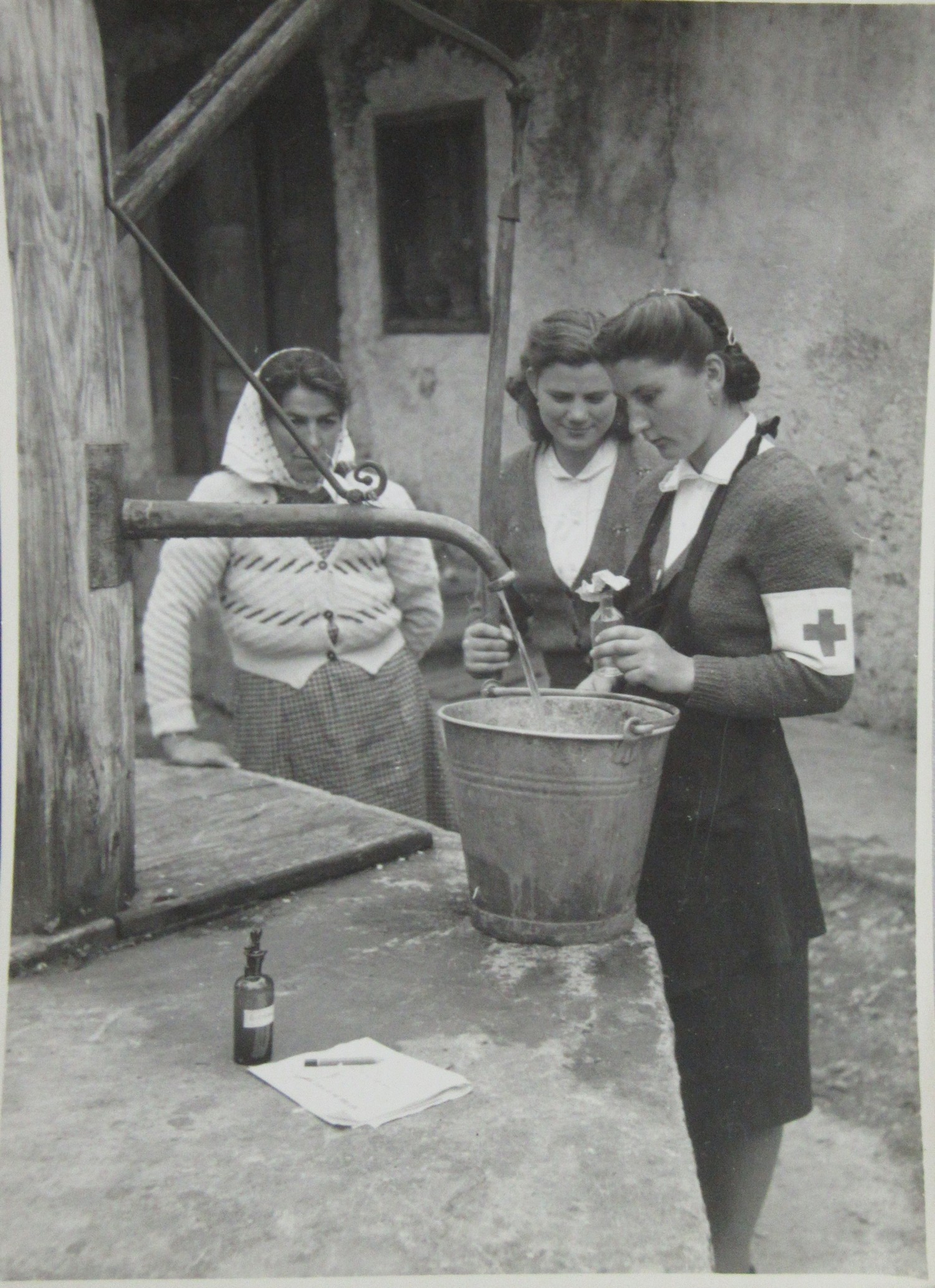 Slika 8: Članici RKS v okviru vaškega tečaja demonstrirata jemanje vzorca
                        za analizo pitnosti vode (petdeseta leta)